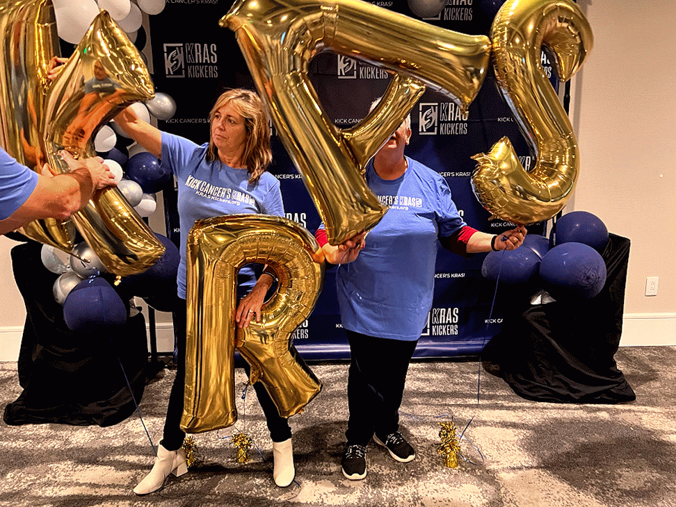 KRAS Kickers community members celebrating at an event with gold letter balloons